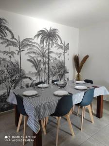 圣菲利普Les Caze de la Mer Cassée的用餐室配有桌椅和棕榈树壁画