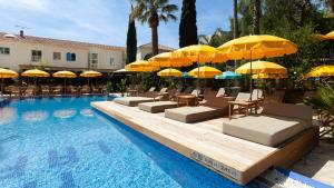 勒拉旺杜Hôtel La Piscine的一个带黄色遮阳伞和躺椅的游泳池和一个游泳池