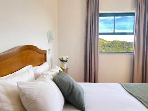 维尼艾什Vinhais Hotel的卧室配有带白色枕头的床和窗户。