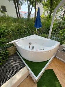 卡奥莱Casa Roberta con favolosa terrazza privata的草上带遮阳伞的白色浴缸