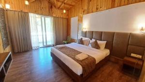 瑞诗凯诗Qcent Woods Resort & Spa, Rishikesh的一间卧室设有一张大床和一个大窗户