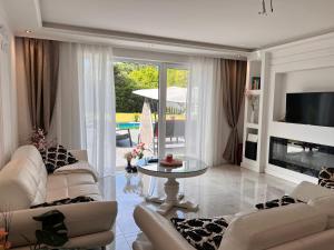 居特斯洛LUXUS-RelaxDays-Apartments的客厅配有白色家具和玻璃桌