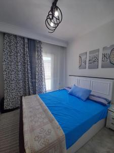 阿莱曼Two Bedrooms for Families only Chalet Sia Lagoon Golf Porto Marina للعائلات فقط شاليه غرفتين كريستال لاجون جولف بورتو مارينا的一间卧室设有蓝色的床和窗户。