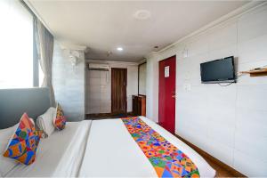 SaluaFabHotel Raj Darbar的卧室配有白色的床,墙上配有电视