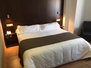 比利亚罗夫莱多卡斯蒂洛酒店的卧室配有一张带白色床单和枕头的大床。