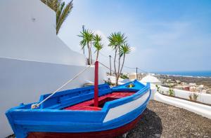 伊亚Sun Angelos Oia - Luxury Cave Suites的蓝红色的船,坐在建筑物的一边