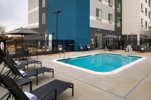 夏洛特Fairfield Inn & Suites by Marriott Charlotte University Research Park的一座带椅子的游泳池以及一座建筑