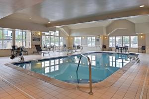 奥罗拉Residence Inn by Marriott Denver Airport at Gateway Park的酒店大堂的游泳池,配有桌椅