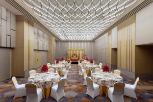 阿姆利则Courtyard by Marriott Amritsar的一个带桌子和白色椅子的大型宴会厅