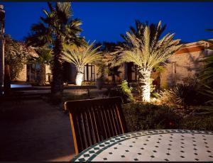 索维拉Villa des Hauts Mogador的一张桌子,晚上有长凳和棕榈树