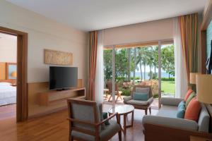 七岩Sheraton Hua Hin Resort & Spa的带电视的客厅和配有床的房间