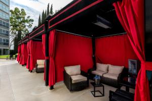洛杉矶Sheraton Gateway Los Angeles Hotel的一个带红色窗帘和椅子的有盖庭院