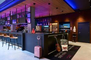布鲁塞尔Moxy Brussels City Center的一间有行李箱的酒吧以及一间有吉他手的酒吧