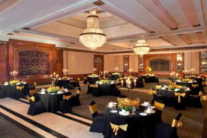 新德里Sheraton New Delhi Hotel的宴会厅配有黑色桌椅和吊灯