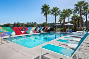 杰克逊维尔杰克逊维尔机场雅乐轩酒店的一个带躺椅的游泳池,棕榈树