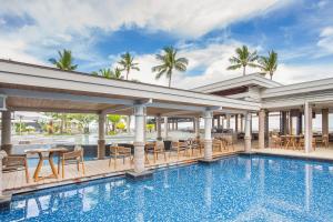 丹娜努Sheraton Fiji Golf & Beach Resort的一座带桌椅的游泳池位于酒店大楼旁