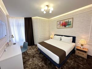 塔什干Garnet Hotel Tashkent的配有一张床、一张书桌和一扇窗户的酒店客房