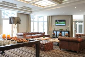 吕埃尔-马尔迈松巴黎竞技场圣克劳德万丽酒店的客厅配有皮革家具和电视