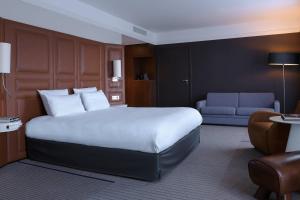 吕埃尔-马尔迈松巴黎竞技场圣克劳德万丽酒店的酒店客房设有一张大床和一张沙发。