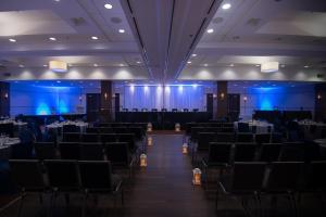 温尼伯南温尼伯喜来登福朋酒店的宴会厅配有桌椅和蓝色灯光