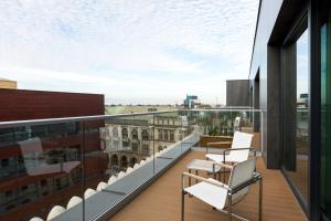 弗罗茨瓦夫弗罗茨瓦夫万豪AC酒店的阳台配有椅子,享有建筑的景致。