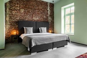 马斯特里赫特Landgoed Kasteel de Hoogenweerth的一间卧室设有一张带砖墙的大床