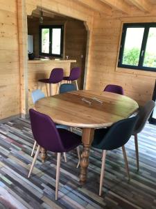AlièzeForest Jura Lodge - Chalet de la Vache的小屋内一张带紫色椅子的木桌