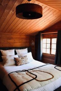 巴纽勒森林L’Hacienda Maison d’hôtes的一间卧室设有一张带木制天花板的大床