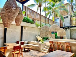 埃斯孔迪多港Nectar Hotel, Cafe, Cowork - Adults Only的一个带沙发和桌子的庭院,并种植了棕榈树