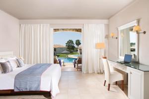 基利尼奥林匹亚金海滩SPA度假酒店的一间卧室配有一张床和一张书桌,还有一个游泳池