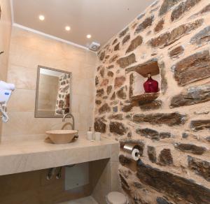 马尔马里Marmari Paradise Resort Hotel的石质浴室设有水槽和石墙