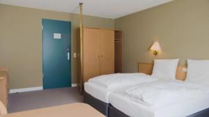 比特堡Hotel Bitburg的一间卧室设有两张床和一扇蓝色的门