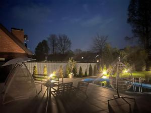 居特斯洛LUXUS-RelaxDays-Apartments的一个带椅子的庭院和夜间游泳池