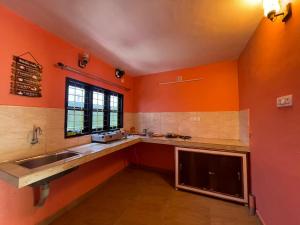 蒙纳Mountain cheers munnar的厨房设有橙色的墙壁、水槽和窗户