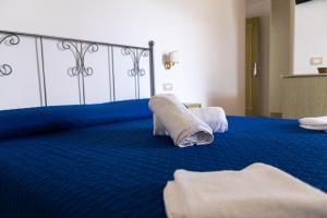 托尔托拉地中海塞纳托别墅酒店的一间卧室配有蓝色的床和毛巾