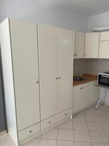 拉里萨Secret Oasis Aptms room1的厨房配有白色橱柜和微波炉