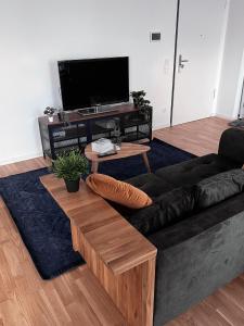 贝尔吉施格拉德巴赫Moderne Wohnung mit Loggia - Neubau 2023的客厅配有黑色沙发和电视