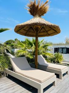 圣马迪拉莫Cabane le Flamant avec jardin, piscine chauffée et parking的甲板上的一把草伞和椅子
