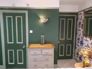 斯坦维尔The Lodge Stanwell的卧室设有绿色的墙壁和白色的梳妆台及门