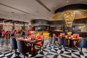 新德里Sheraton New Delhi Hotel的一间带桌椅的餐厅和一间酒吧