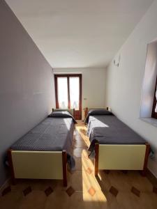 帕尔盖利亚Piccola Mansarda的带2扇窗户的客房内的2张床