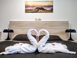 哈拉霍夫Horský rodinný apartmán 2KK s velkou terasou, s wellness, snídaní na pokoj a s vlastním parkováním v garáži - by Relax Harrachov的一张有两只天鹅的睡床,看起来像心脏