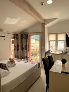 布德瓦Pearl Apartments的一间卧室配有一张床、一张桌子和一个窗户。