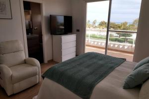 Barrio-MarVilla de lujo frente al mar的一间卧室配有一张床、一把椅子和电视