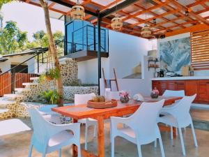 BariliLas Terrazas de Barili的户外用餐室配有木桌和白色椅子