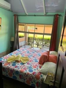 雅科Villas Paraíso Jacó B20的一间卧室配有一张带五颜六色的被子的床和窗户