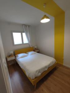 卢尔德Appartement Le Secret, Proche Sanctuaires, Climatisé的一间卧室配有一张带白色床单的床和一扇窗户。
