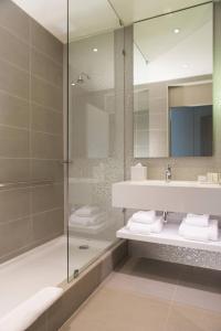 圣地亚哥圣地亚哥拉斯孔德斯万怡酒店的带淋浴、盥洗盆和镜子的浴室