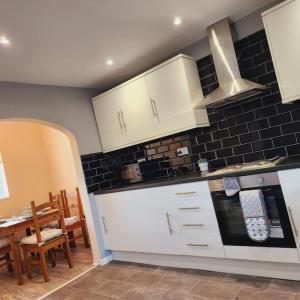JarrowSunny South Shields House的厨房配有白色橱柜、桌子和炉灶。
