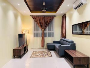 瓜拉丁加奴Renai Homestay Ladang Tanjung Kuala Terengganu with POOL的客厅配有蓝色的沙发和电视